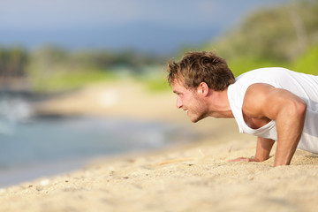 Push-ups - man fitness model training on beach