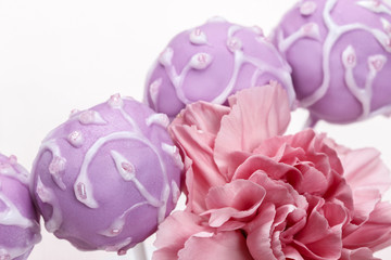 Lilac cake pops decorated lavishly decorated with icing.