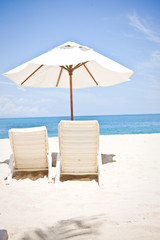 Two chairs under an umbrella on an empty beach