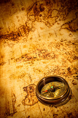 Obraz premium Vintage kompas leży na starożytnej mapie świata.