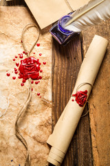 Closeup of old scrolls,  sealing wax and blue ink on wooden tabl