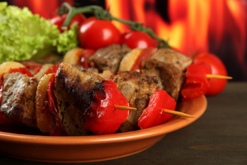 tasty grilled meat and vegetables on plate, on fire background