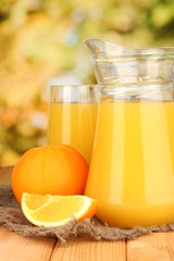 Full glass and jug of orange juice and oranges