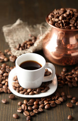 Cup of coffee and pot on wooden background