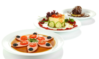 Small portions of food on big white plates isolated on white