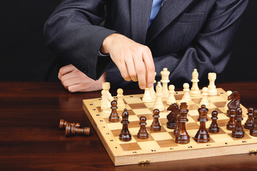 Young business man playing chess on black background