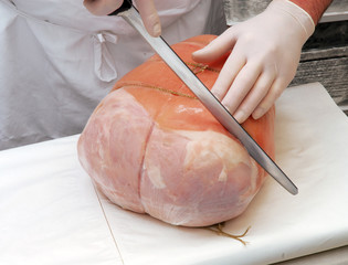 Carnicero cortando una porción de jamón cocido Italiano.
