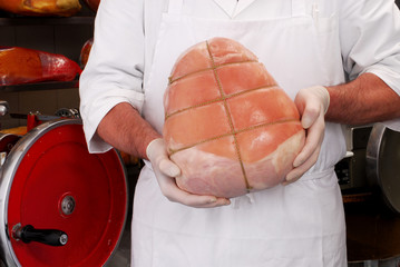 Carnicero sujetando una porción de jamón cocido Italiano.