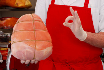 Carnicero sujetando una porción de jamón cocido Italiano.