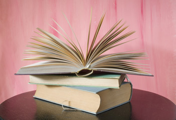 open book on a table, pink background
