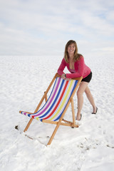 Woman with a colourful deckchair in the snow