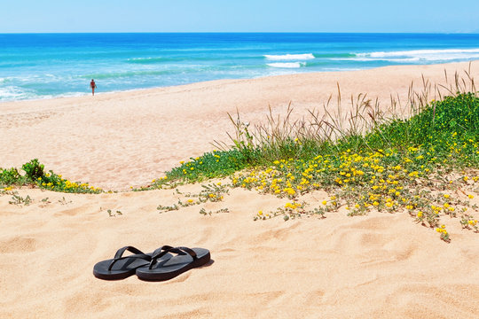 Flip-flops on the background of the beautiful beach and the sea.