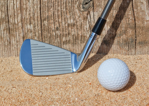 Golf stick and ball support wooden close-up on the sand.