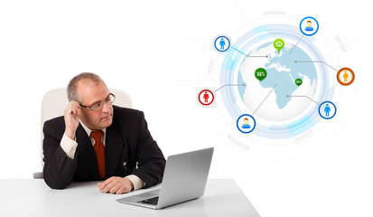 businessman sitting at desk and looking laptop with globe and so
