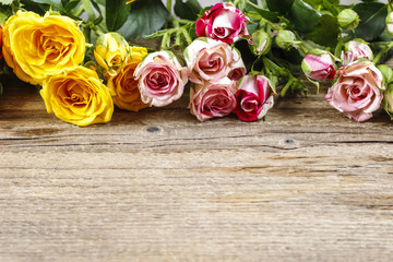 Wooden surface with copy space decorated with colorful roses.