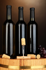 Naklejka premium Wine and corks on barrel on brown background