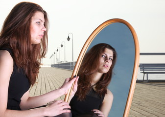 thoughtful woman looks at the reflection in mirror