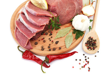 Raw meat, vegetables and spices on a wooden cutting board isolat