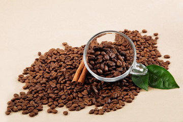 Glass cup with coffee beans and cinnamon sticks.