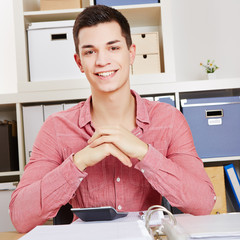 Lachender Student sitzt am Schreibtisch