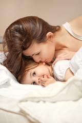 Fototapeta na wymiar A happy family. Young Woman and litle girl in bed