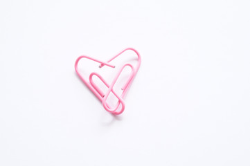 Office romance. Pink paperclips forming a heart.