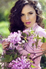 Naklejka premium Young brunette woman with lilac flowers, Outdoors portrait