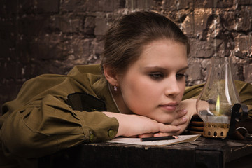 Soviet female soldier in uniform of WWII looking at the fire.