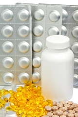 Yellow liquid capsules and silvery plates of medicines 