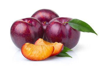 Ripe purple plum fruits with green leaves isolated