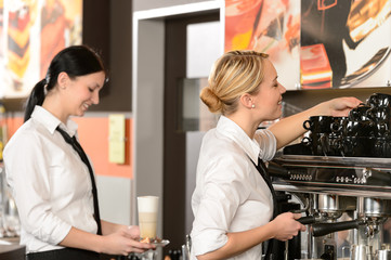 Fototapeta na wymiar Two waitresses serving coffee with machine