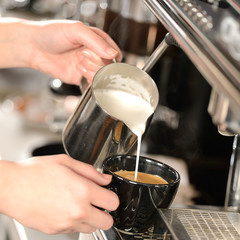 Fototapeta na wymiar Waitress hands pouring milk making cappuccino