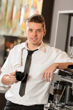 Attractive waiter leaning on espresso machine