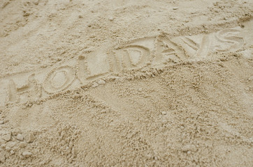 Word holidays written on sandy beach