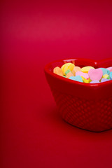 a candy dish is filled with heart candy on red