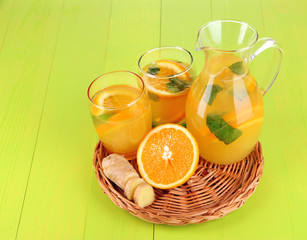 Orange lemonade in pitcher and glasses on wooden table close-up