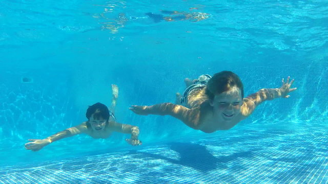 Two Boys Jumping Into Pool Then Swims Underwater To Camera