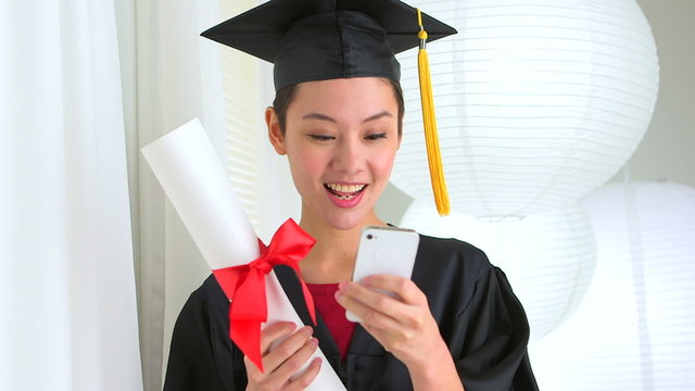Mixed Race Asian graduate with smart phone