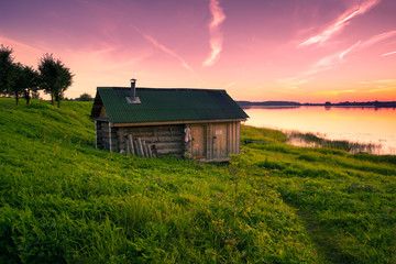 Little lone house on banks of the river at sunset in silence