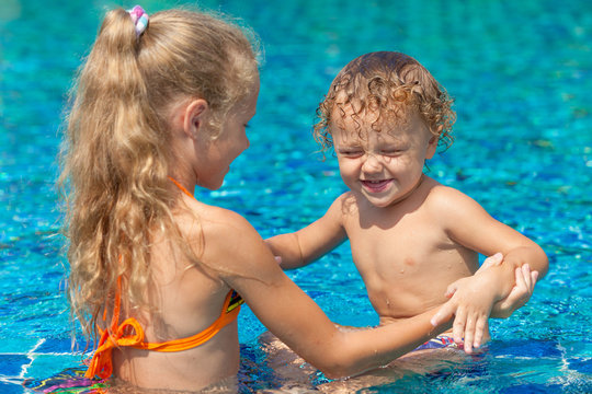 little girl and little boy playing in the swimming  pool