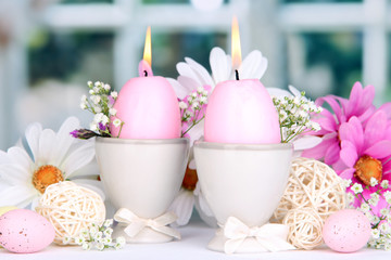 Fototapeta na wymiar Easter candles with flowers on window background