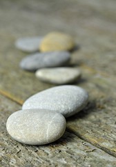 Fototapeta na wymiar A row of pebbles lying on a wooden background