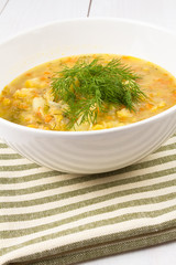 Yellow pea soup in bowl on white wooden background