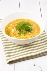 Yellow pea soup in bowl on white wooden background