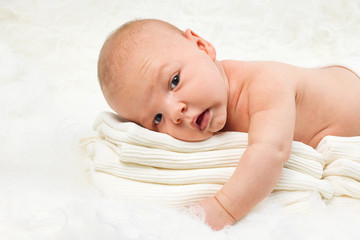 Cute baby boy lying on stack of towels