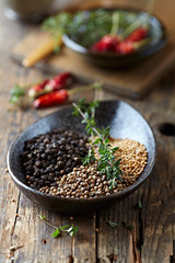 Assorted spices and fresh thyme in a ceramic dish