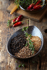 Assorted spices and fresh thyme in a ceramic dish