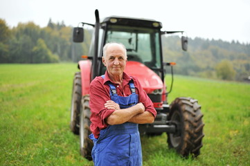Trotse boer die voor zijn rode tractor staat