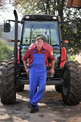 Proud farmer standing in front of his red tractor