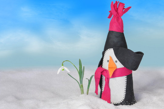Lustiger Pinguin und Schneeglöckchen im Schnee